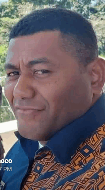 a close up of a man 's face wearing a blue and orange shirt .