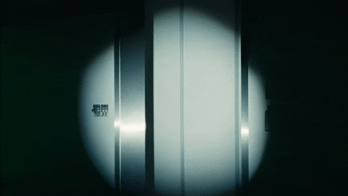 a dark room with a light shining on a door that says ' emergency exit ' on it