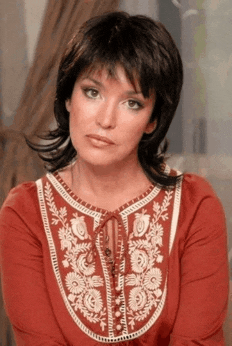 a woman wearing a red shirt with white embroidery on the neckline