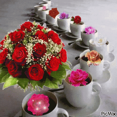 a bouquet of red roses sits on a table next to cups of coffee with flowers in them