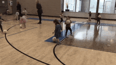a group of children are playing with soccer balls on a court