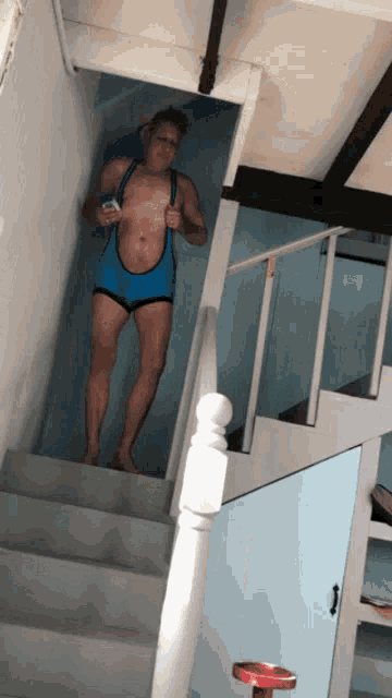 a man in a blue bodysuit is standing on a set of stairs holding a cell phone