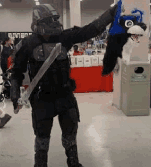 a man in a costume is holding a stuffed animal in front of a trash can that says jumbo