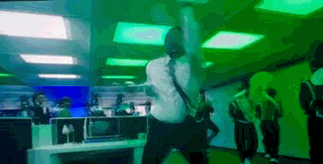 a man in a white shirt and tie is dancing in an office with green lights .