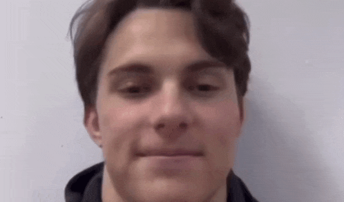 a close up of a young man 's face with a hoodie on .