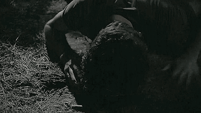 a man is laying on his stomach on the ground in the dark .