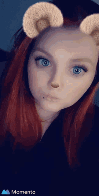a woman with red hair and blue eyes is wearing a momento sticker on her face