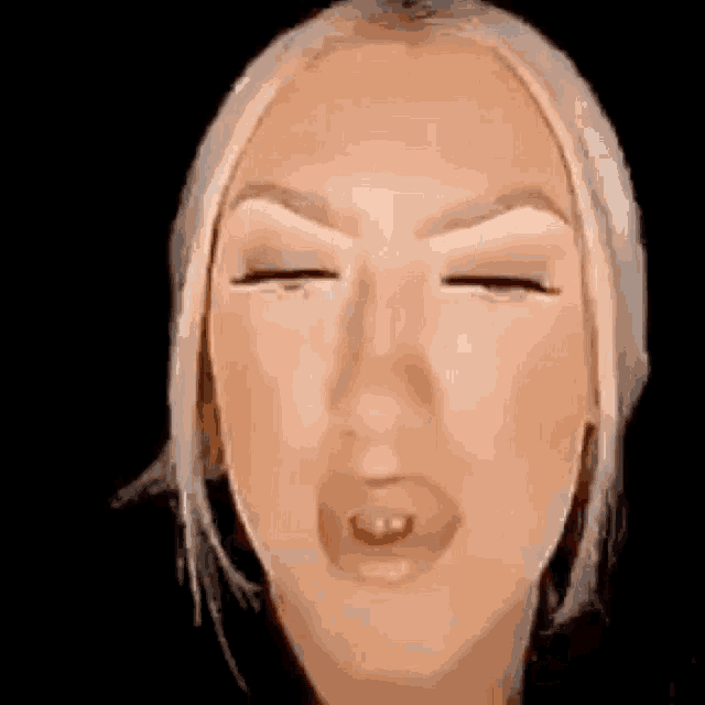 a woman with blonde hair is making a funny face with her eyes closed and her mouth open .