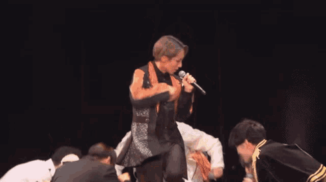 a woman singing into a microphone with a group of people behind her