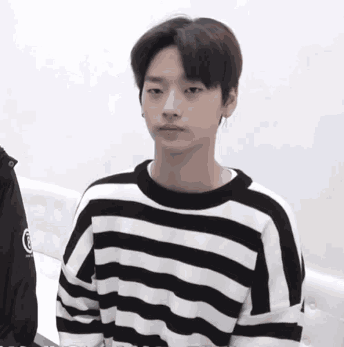 a young man wearing a black and white striped sweater with the letter r on the sleeve