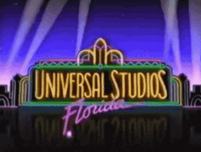 a neon sign for universal studios florida with a city in the background