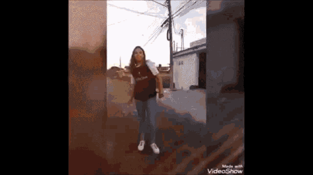 a woman is standing on a street holding a bottle of water .