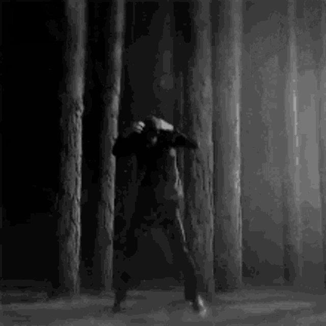 a black and white photo of a man dancing in the woods .