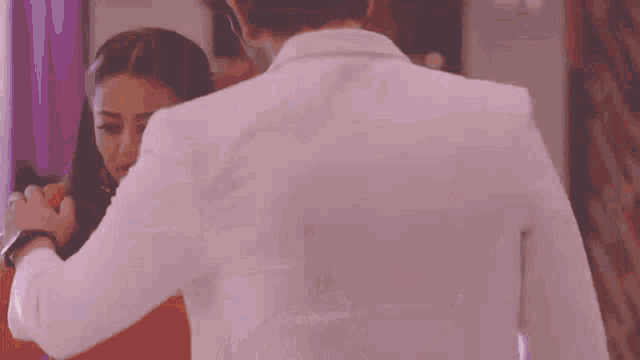 a man in a white shirt is kissing a woman in a purple room .