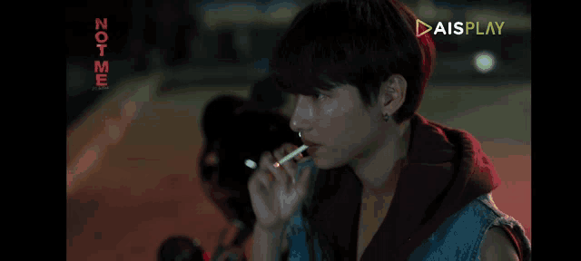 a man is smoking a cigarette in front of a screen that says not me