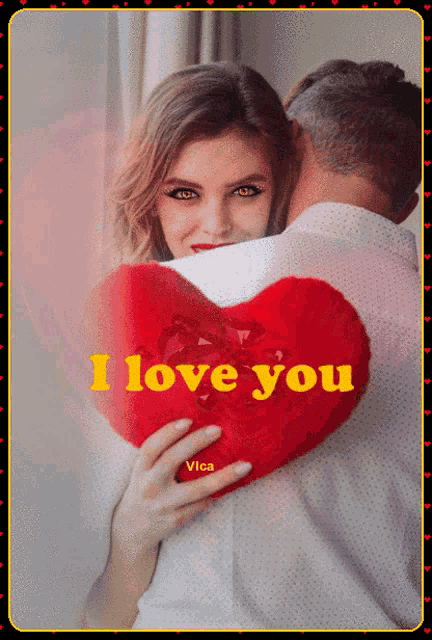 a woman holding a heart shaped pillow that says " i love you " on it