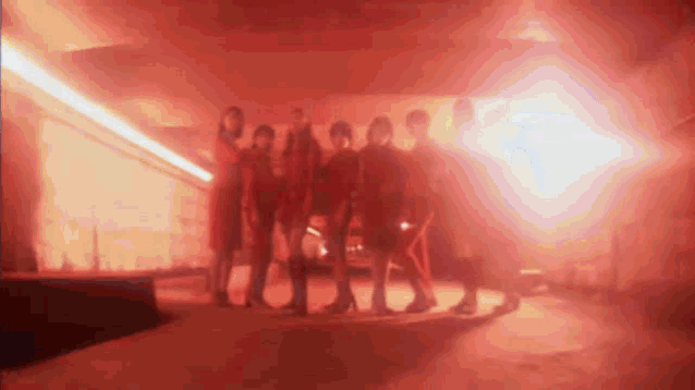 a group of people are standing in front of a red light .