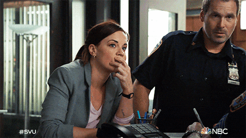 a woman sitting at a desk talking on a phone next to a police officer with #svu written on the bottom