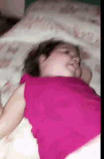a woman in a pink shirt is sleeping in bed