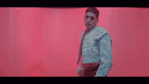 a man in a blue jacket and black pants is dancing on a red floor .