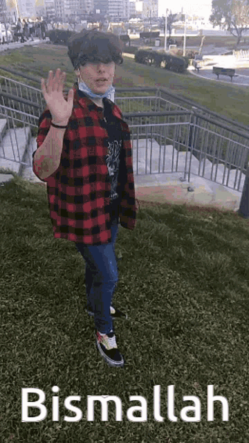 a person wearing a mask and a plaid shirt is standing in the grass with the words bismallah above them