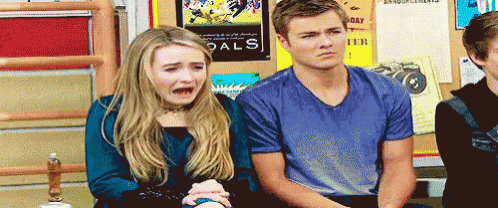 a boy and a girl are sitting next to each other in front of a goals poster