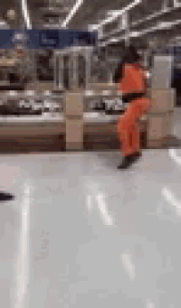 a person in orange pants is jumping in a store .
