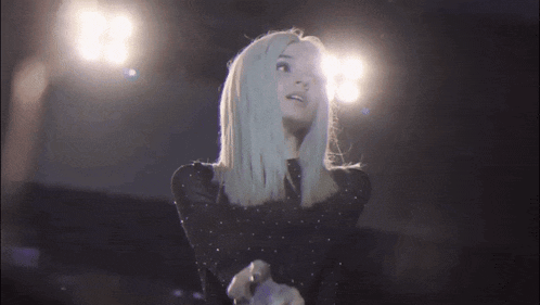 a woman with blonde hair is singing into a microphone