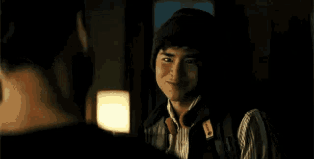 a young man wearing headphones and a beanie is smiling at another man .