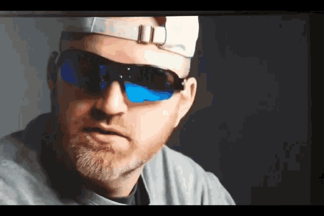 a man wearing sunglasses and a hat is looking at the camera