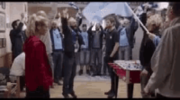 a group of people are standing in a room holding flags and waving them in the air .