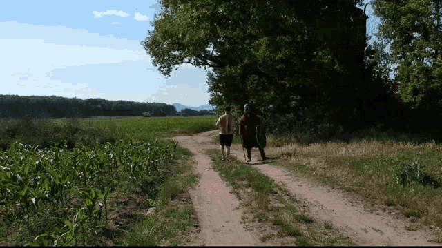 two people walking down a dirt road with a shield