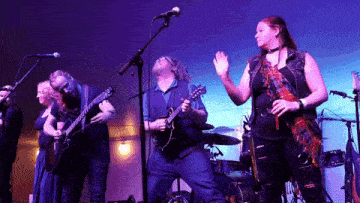 a group of people playing guitars and singing into microphones on stage