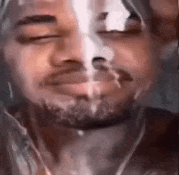 a close up of a man smoking a cigarette with his eyes closed and a beard .