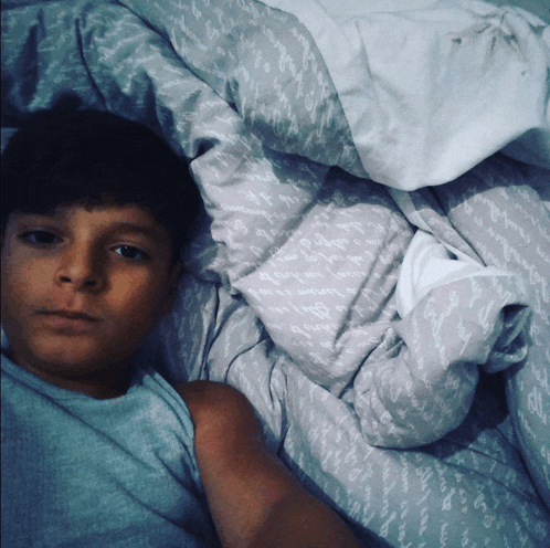 a boy is laying on a bed with a blanket that says " i love you "
