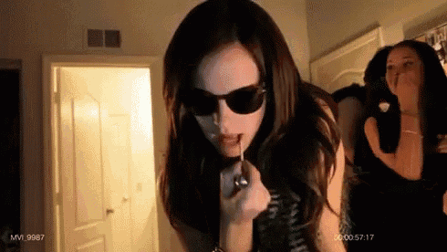 a woman wearing sunglasses is applying lip gloss in a room with a watermark that says mvi 997