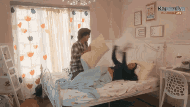 a woman is laying on a bed while a man throws a pillow