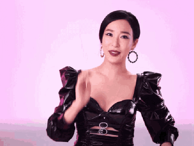 a woman wearing a black dress with a plunging neckline and earrings