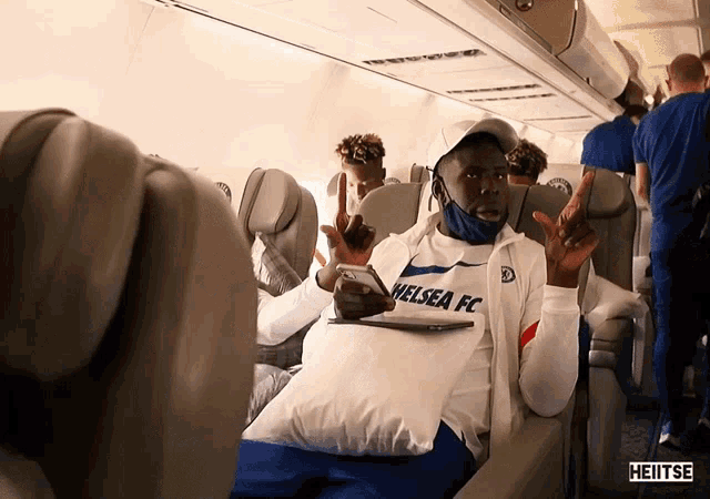 a man in a chelsea fc shirt sits on a plane