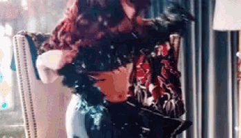 a woman is sitting in a chair with a vase of flowers in front of her .