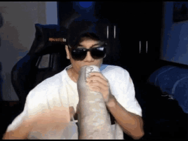 a man wearing sunglasses and a hat drinks from a can