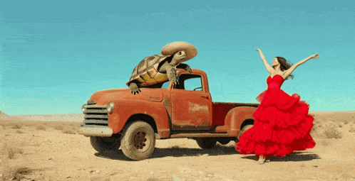 a woman in a red dress is standing next to a truck with a turtle on top of it