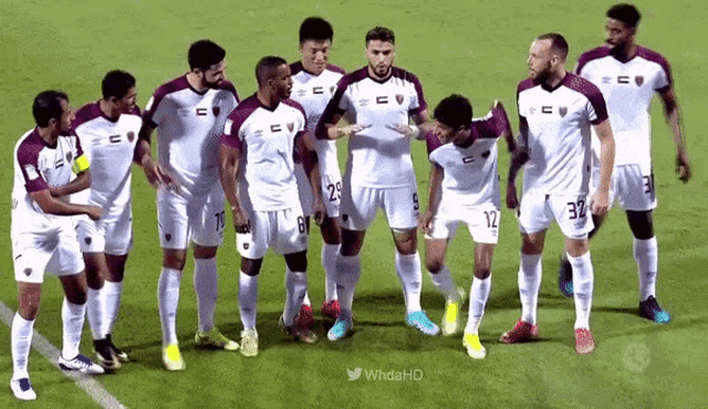 a group of soccer players are standing on a field and one of them has the number 32 on his jersey