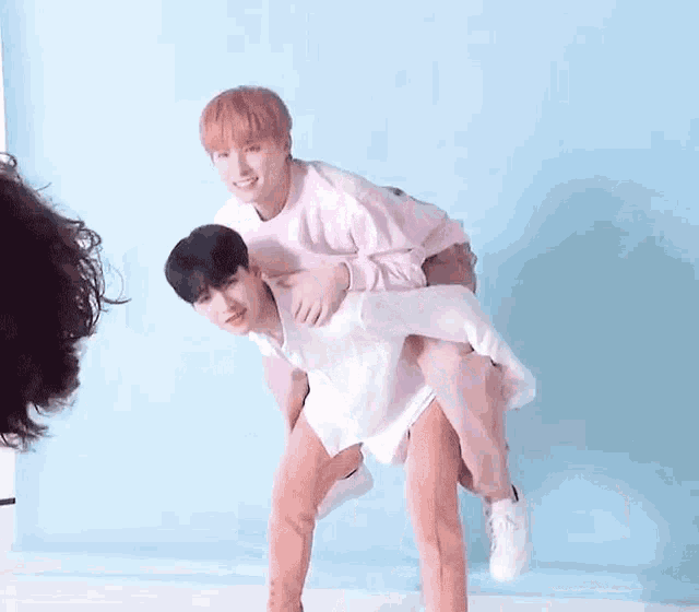 a man is carrying another man on his back while standing next to each other .