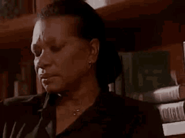 a close up of a woman sitting in front of a bookshelf .