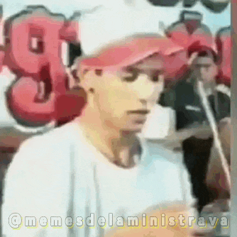 a man wearing a red hat is standing in front of a sign that says g on it .