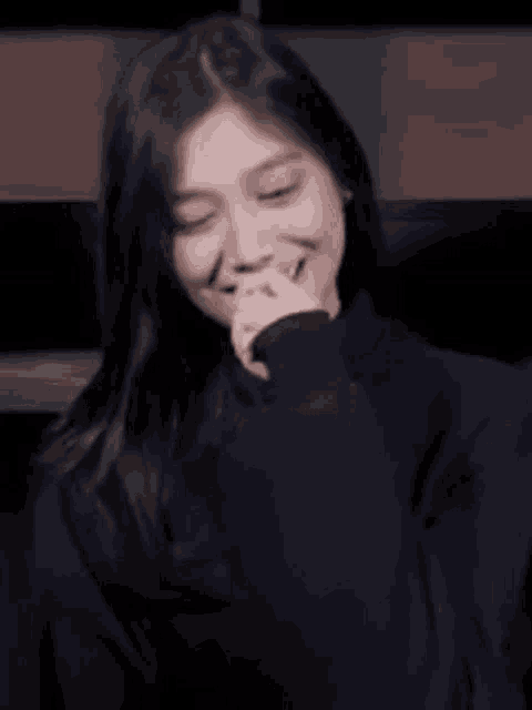a woman is covering her mouth with her hand and laughing .