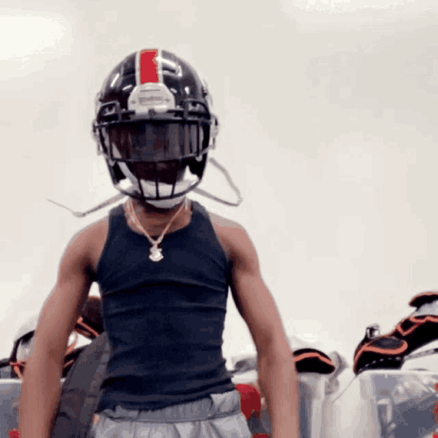 a man wearing a black football helmet with a red and white stripe