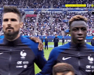 two soccer players are standing next to each other on a field .