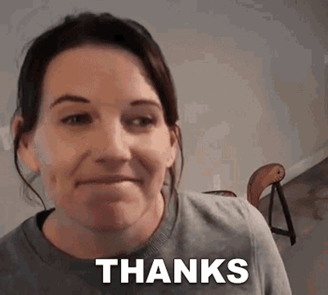 a woman is smiling and making a face while holding a sign that says thanks .